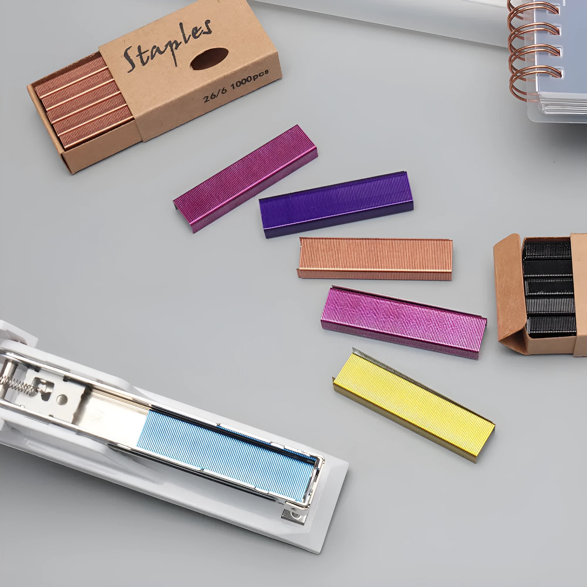 Box of 1000 metal office staples in rose gold, black, purple, and rose red colours.