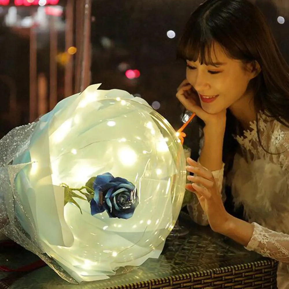 Transparent LED luminous balloon rose bouquet with artificial flowers and integrated lights for party decoration.
