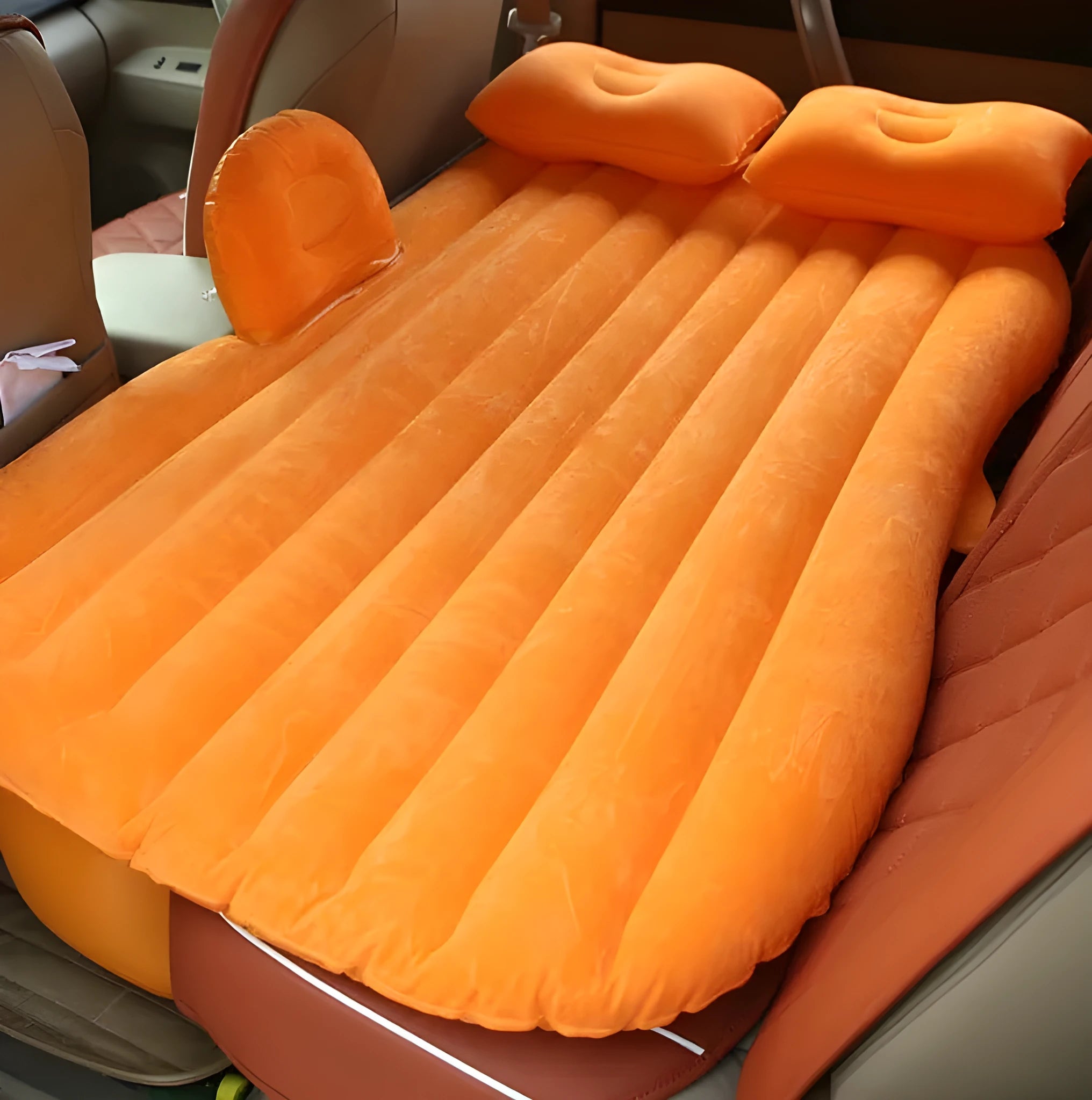 Black inflatable car bed with flocking material and two pillows, shown inside a car.