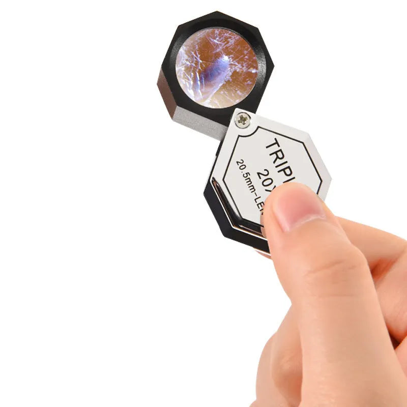 Handheld metal magnifying glass with optical glass lens for jewellery, stamp, and coin identification.