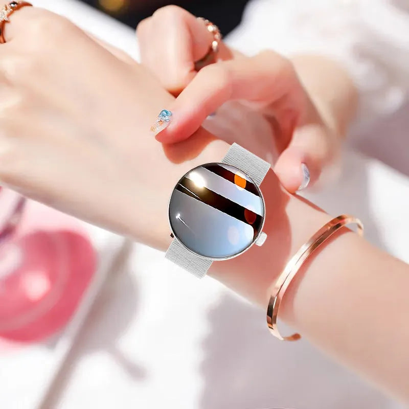 Circular smartwatch for women with metal strap and colour touchscreen on a wrist.