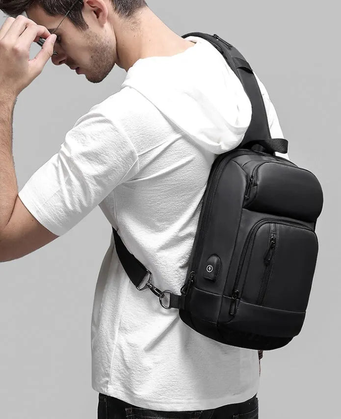 Black PVC outdoor shoulder bag with air cushion strap showing internal computer pocket and organisational compartments