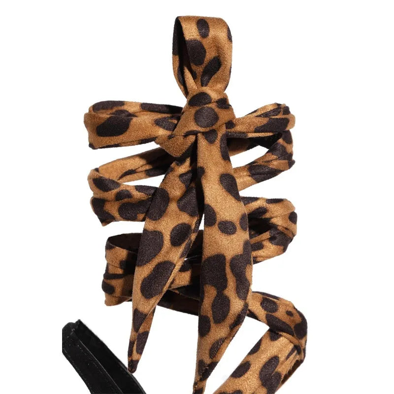 Light brown leopard print women's high-heel sandals with cross straps and a fine high heel.