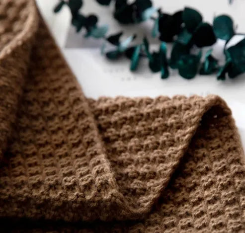 Nordic-style beige acrylic blanket with fringed knit ball detail laid flat.