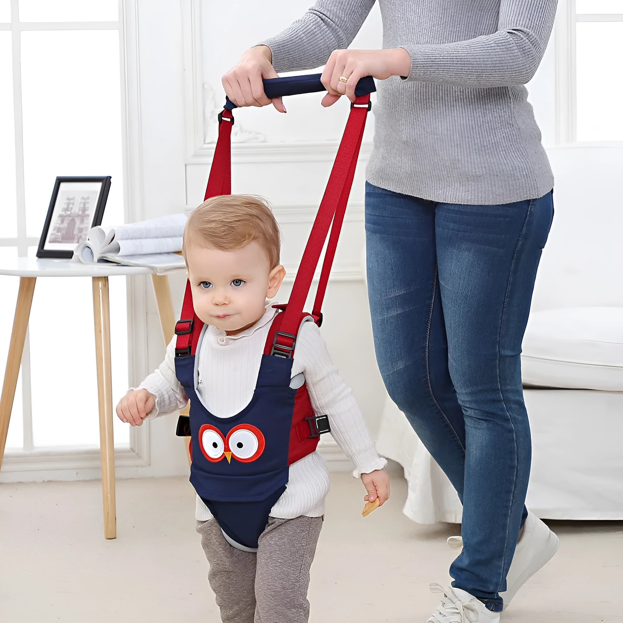 Blue cotton baby walking harness belt with straps, shown being used to support a toddler learning to walk.