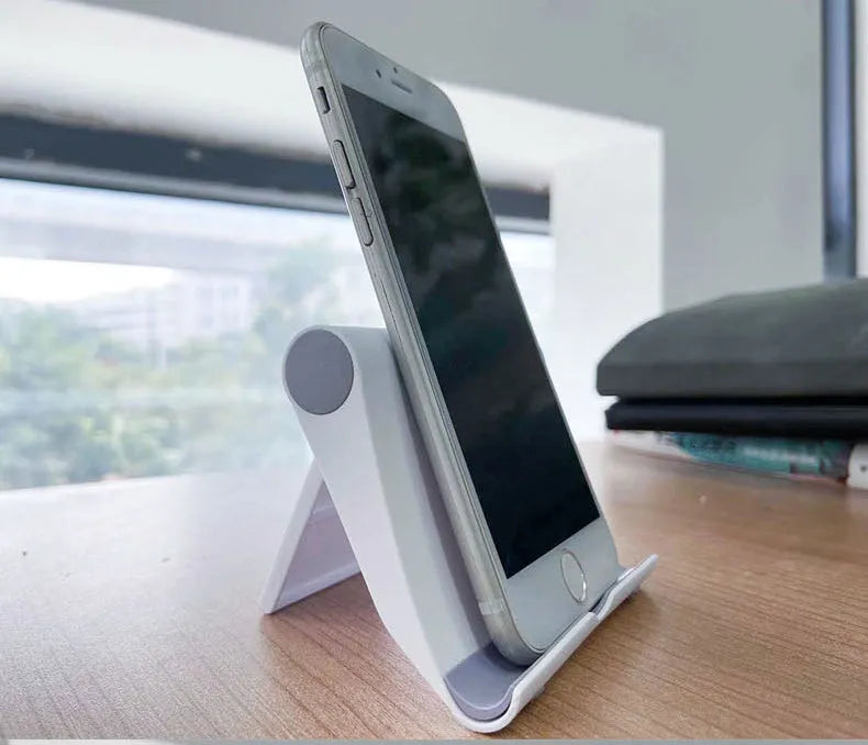 A black PE plastic folding stand holding a mobile phone at an angle, showing its compact design.