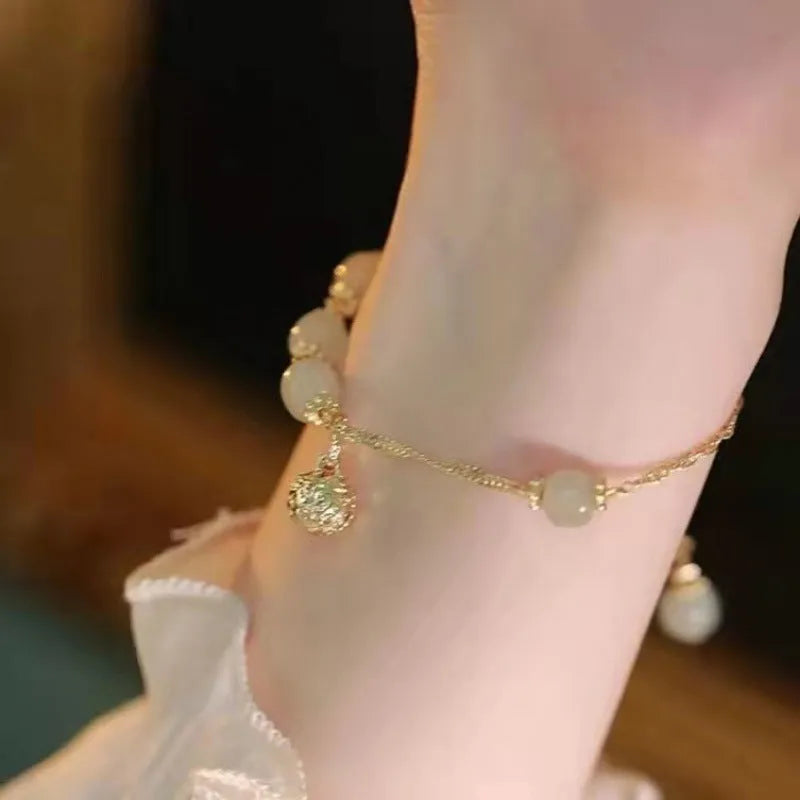 A Chinese style glass bracelet with bamboo leaf and bead designs on a wrist.