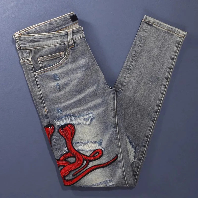 Men's vintage washed slim fit jeans with distressed holes and embroidered patch detail in old colour.