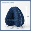 Heart-shaped dark blue memory foam leg pillow for adults on a bed.