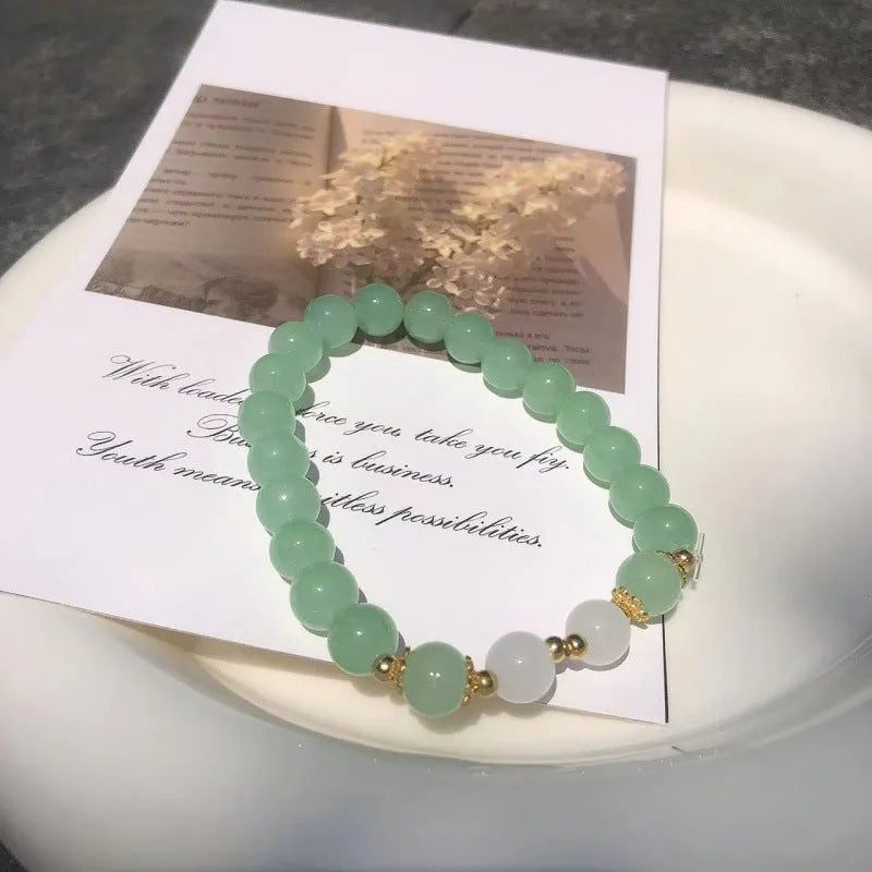 A Chinese style glass bracelet with bamboo leaf and bead designs on a wrist.