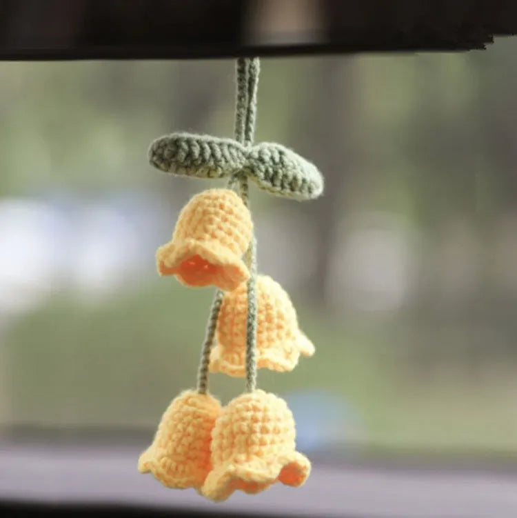 Green and white knitted car plant decoration with hanging rope on car dashboard