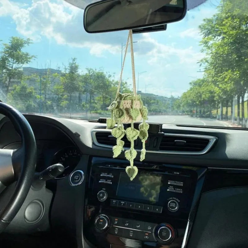 Green and white knitted car plant decoration with hanging rope on car dashboard