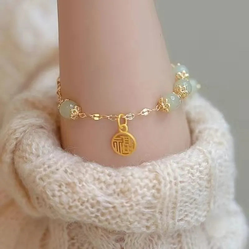 A Chinese style glass bracelet with bamboo leaf and bead designs on a wrist.