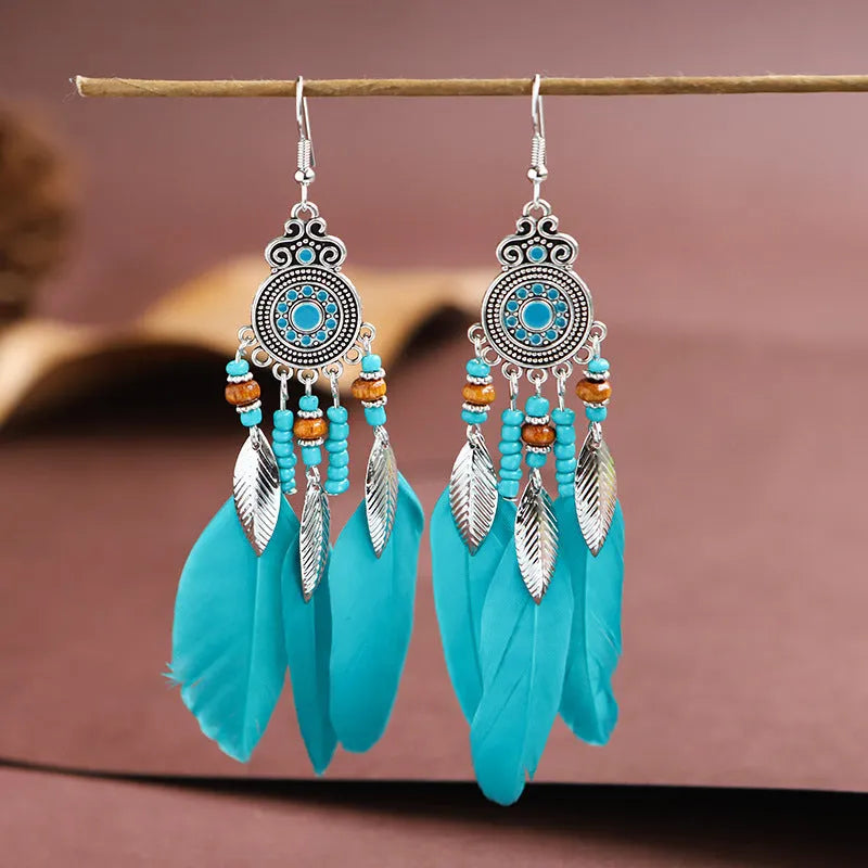 Close-up of a pair of bohemian-style feather-shaped earrings with a leaf pattern, in an alloy electroplated finish.