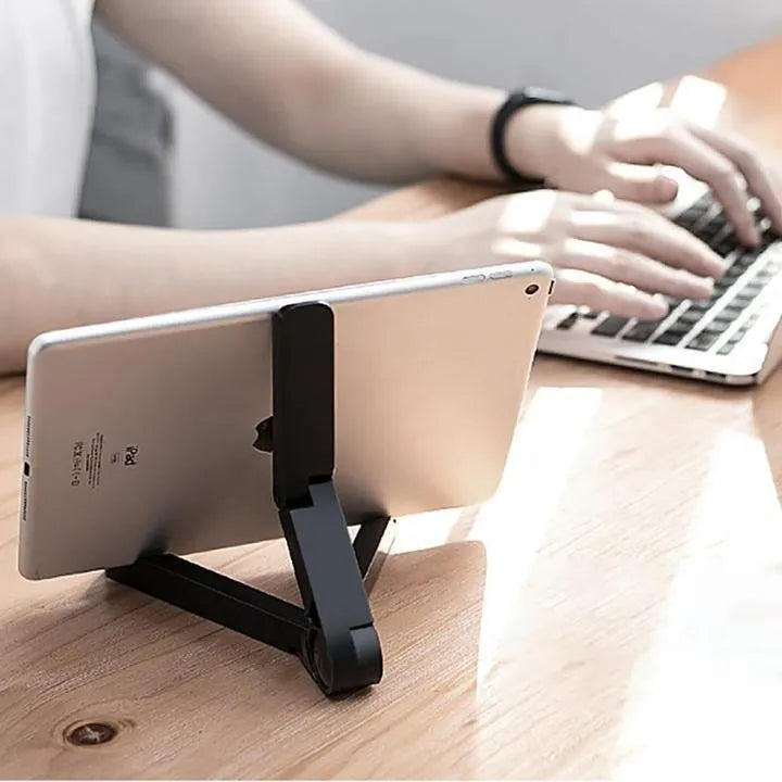 Black foldable tablet holder open in landscape mode holding a smartphone, showing its adjustable angle and non-slip base.