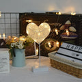 Rattan and copper wire LED table lamp in a star shape on a bedside table.