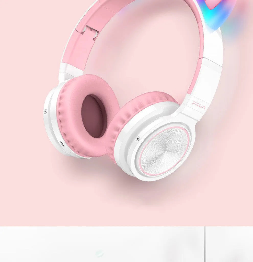 Pink and white wireless Bluetooth over-ear headset with a braided cable on a grey background.