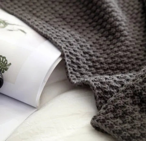 Nordic-style beige acrylic blanket with fringed knit ball detail laid flat.