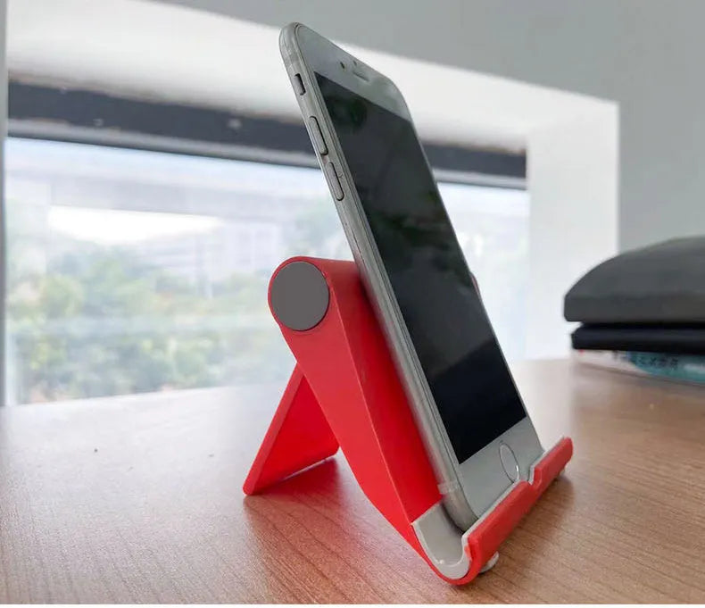 A black PE plastic folding stand holding a mobile phone at an angle, showing its compact design.