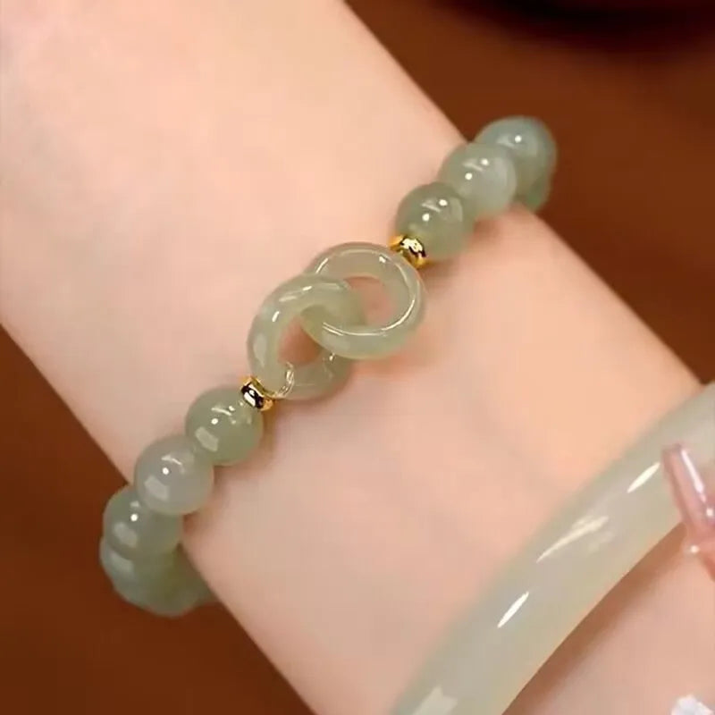 A Chinese style glass bracelet with bamboo leaf and bead designs on a wrist.