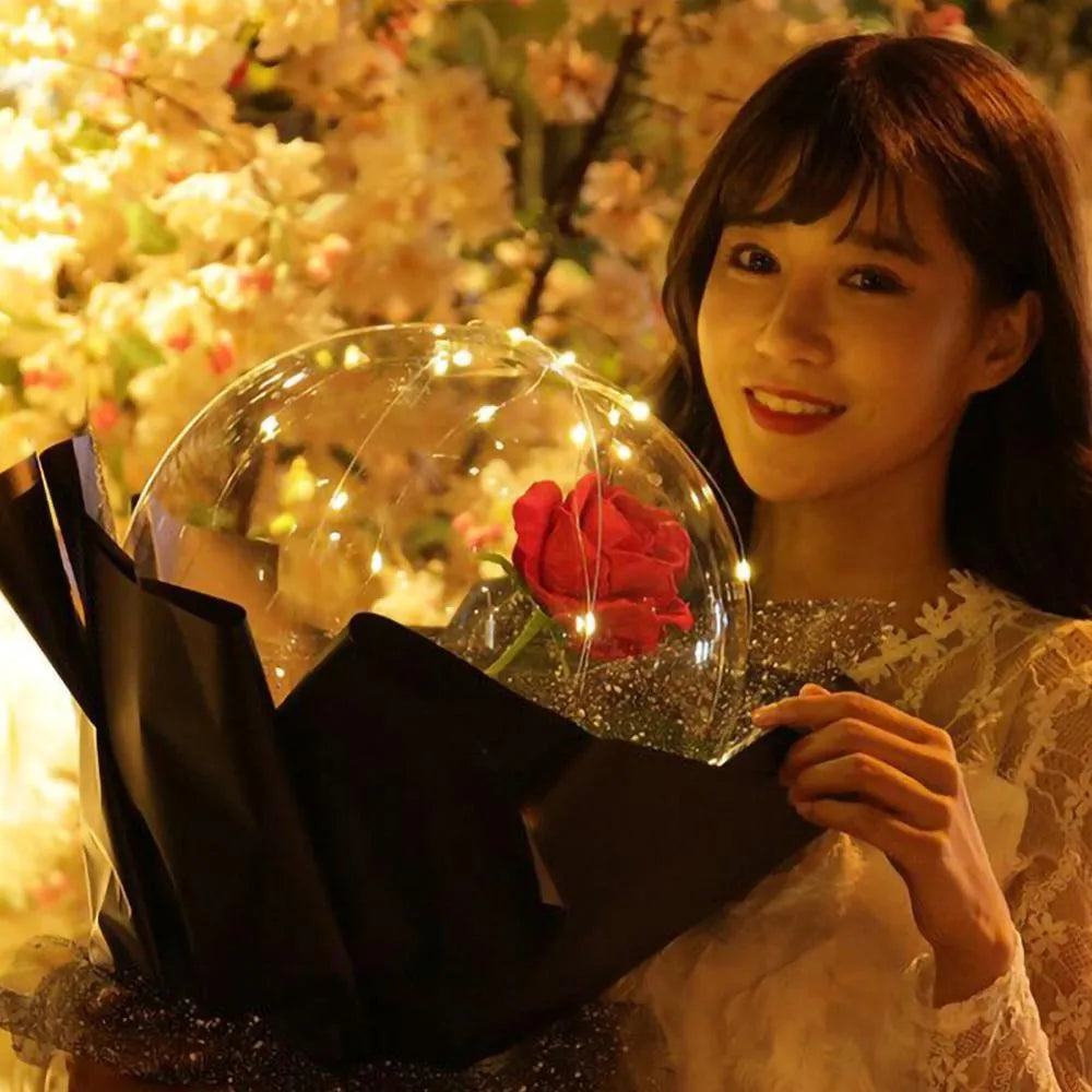Transparent LED luminous balloon rose bouquet with artificial flowers and integrated lights for party decoration.