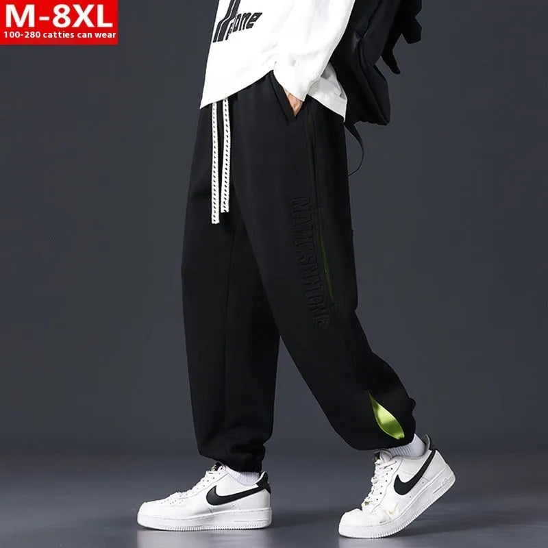 Man wearing loose grey-green cotton trousers with a banded ankle cuff and stitching detail.
