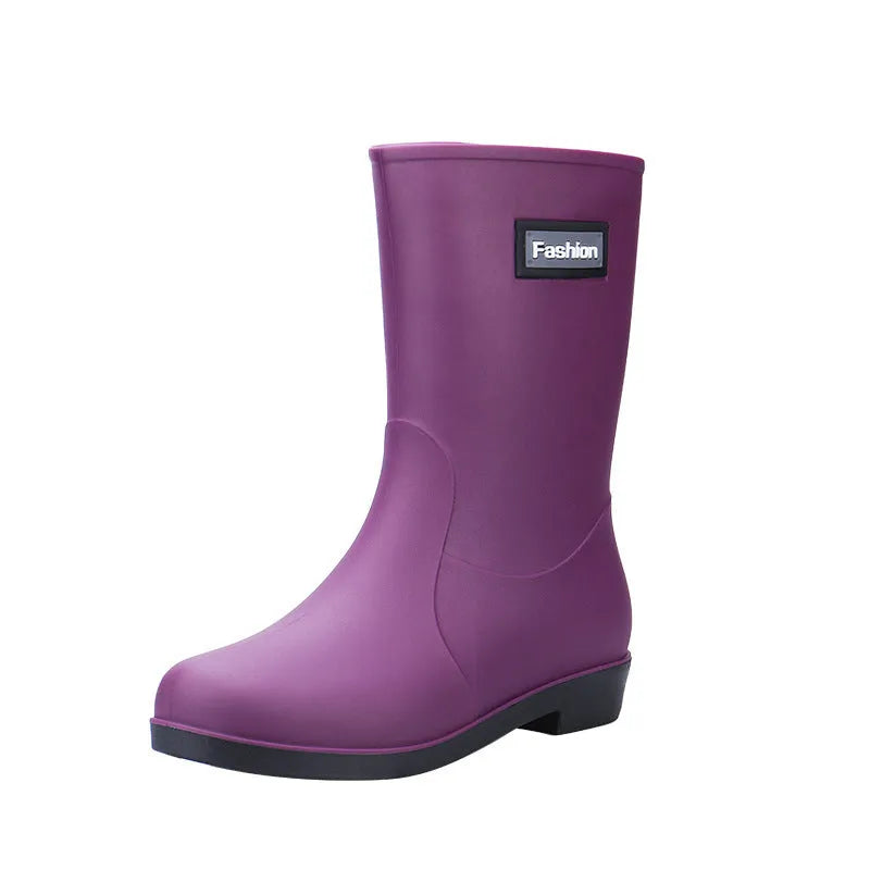 Women's black PVC mid-calf rain boot with low heel on a wet surface