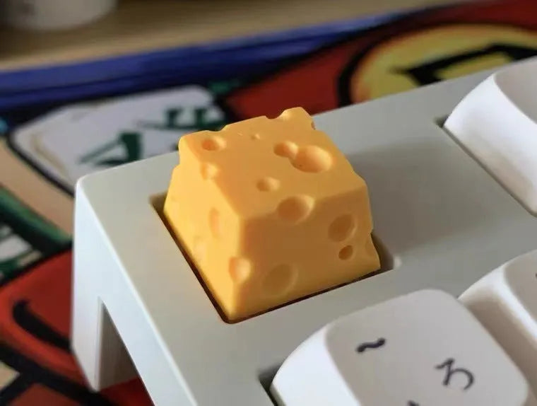 Close-up of a yellow solid resin cheese-themed keycap for mechanical keyboards.