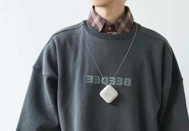 Pink and blue wearable USB air purifier necklace shown on a person, with dimensions 1.5 by 5.7 by 4.5 cm.