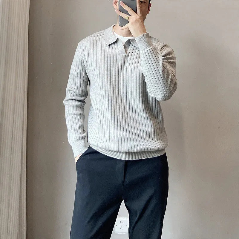 Man wearing a loose grey knitted pullover sweater with long sleeves, showing textured fabric detail.