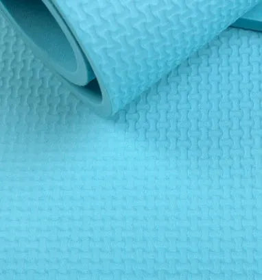Red EVA fitness yoga mat showing texture and thickness, rolled partially with carry bag.