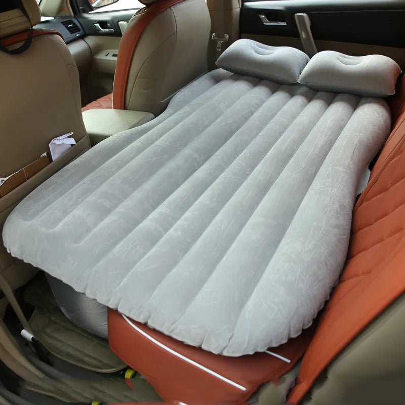 Black inflatable car bed with flocking material and two pillows, shown inside a car.