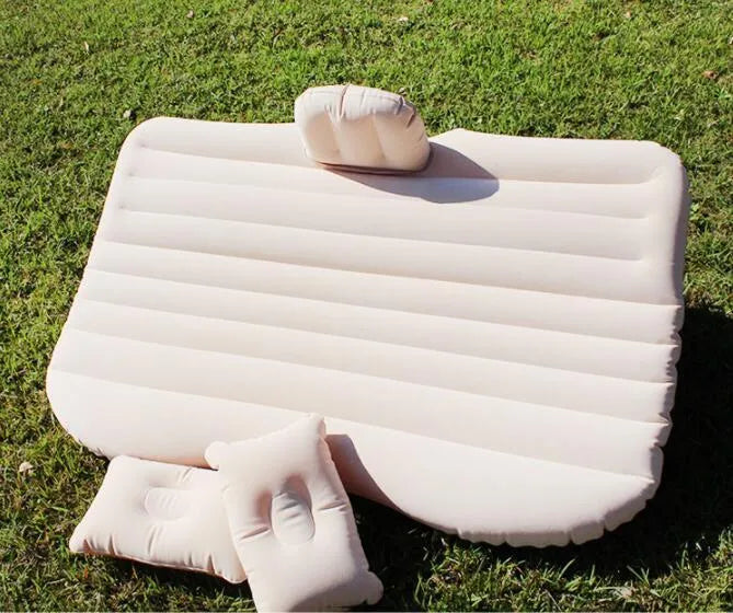 Black inflatable car bed with flocking material and two pillows, shown inside a car.