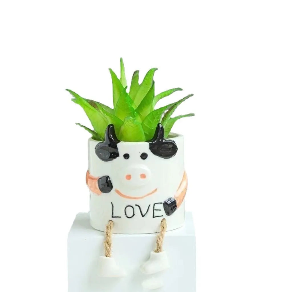 Ceramic cartoon-style succulent flowerpot with hanging foot design on desktop