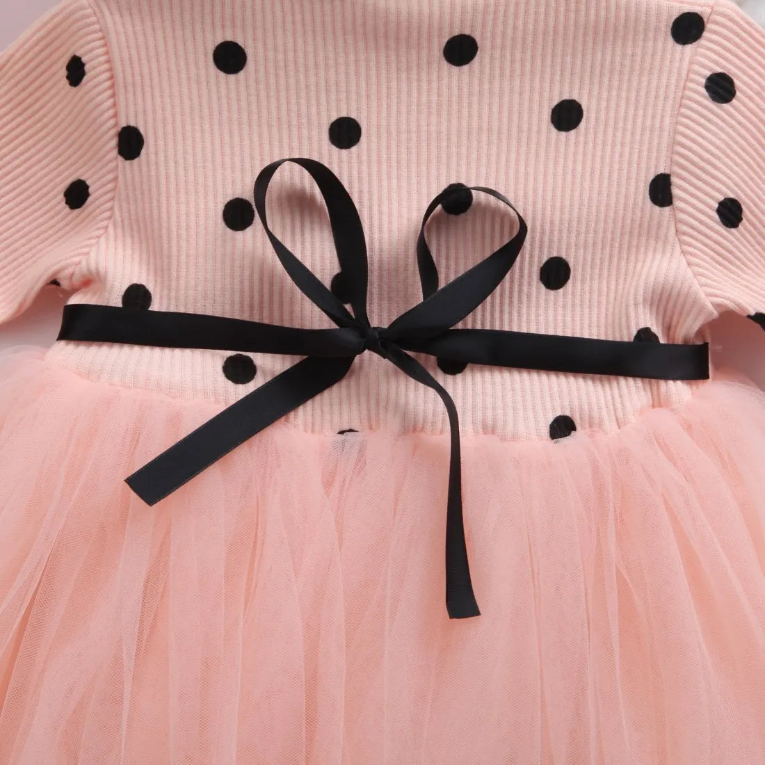 Baby girl wearing a long sleeve white tutu lace dress for a christening or birthday party.