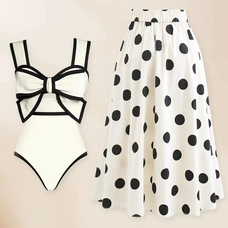 Women's black one-piece swimsuit with a white bow and round skirt on a mannequin, front view.