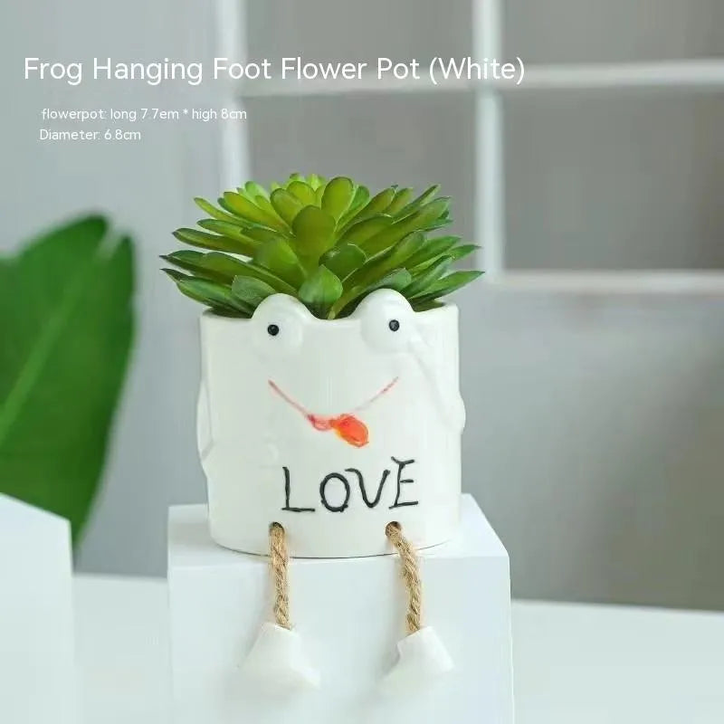 Ceramic cartoon-style succulent flowerpot with hanging foot design on desktop
