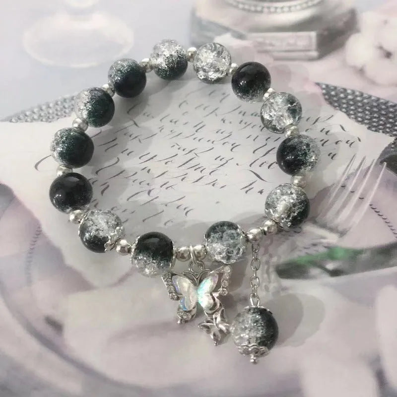 A Chinese style glass bracelet with bamboo leaf and bead designs on a wrist.