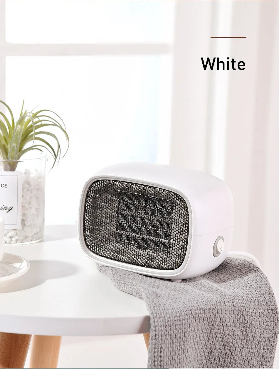 Green mini PTC ceramic heater with metal mesh front on a wooden desk