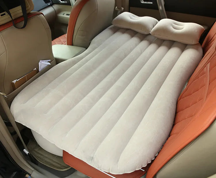 Black inflatable car bed with flocking material and two pillows, shown inside a car.