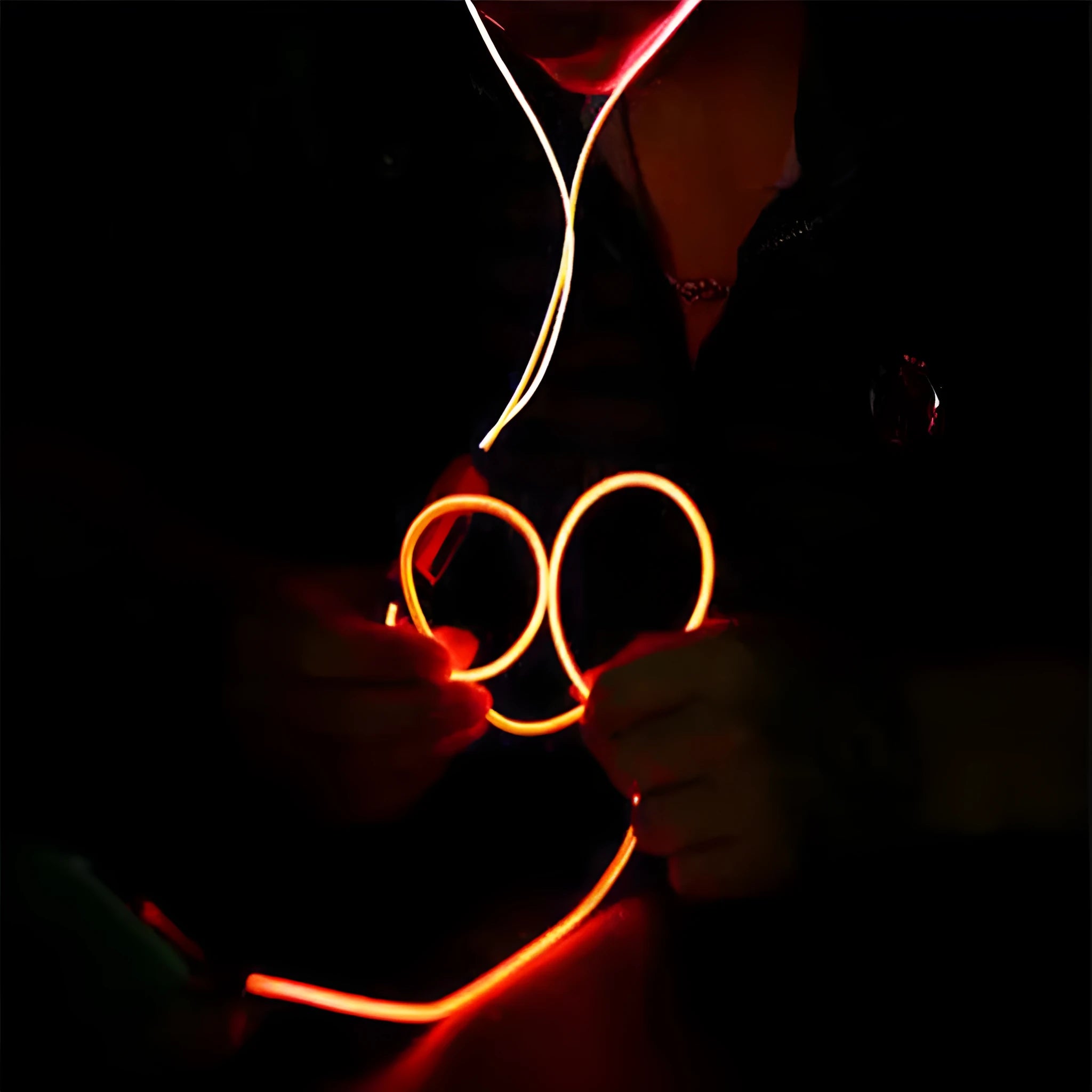 Close-up of blue LED earphones with aluminium alloy shells lit up, showing 3.5mm plug and inline remote.
