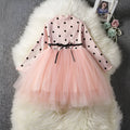 Baby girl wearing a long sleeve white tutu lace dress for a christening or birthday party.