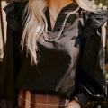 Black long sleeve blouse with V-neck and ruffle detailing on the sleeves.