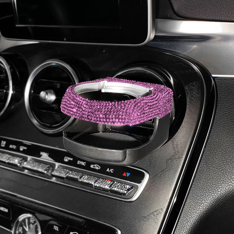 Sparkling rhinestone car cup holder bracket clipped to a vehicle air vent, shown in pink diamond colour.