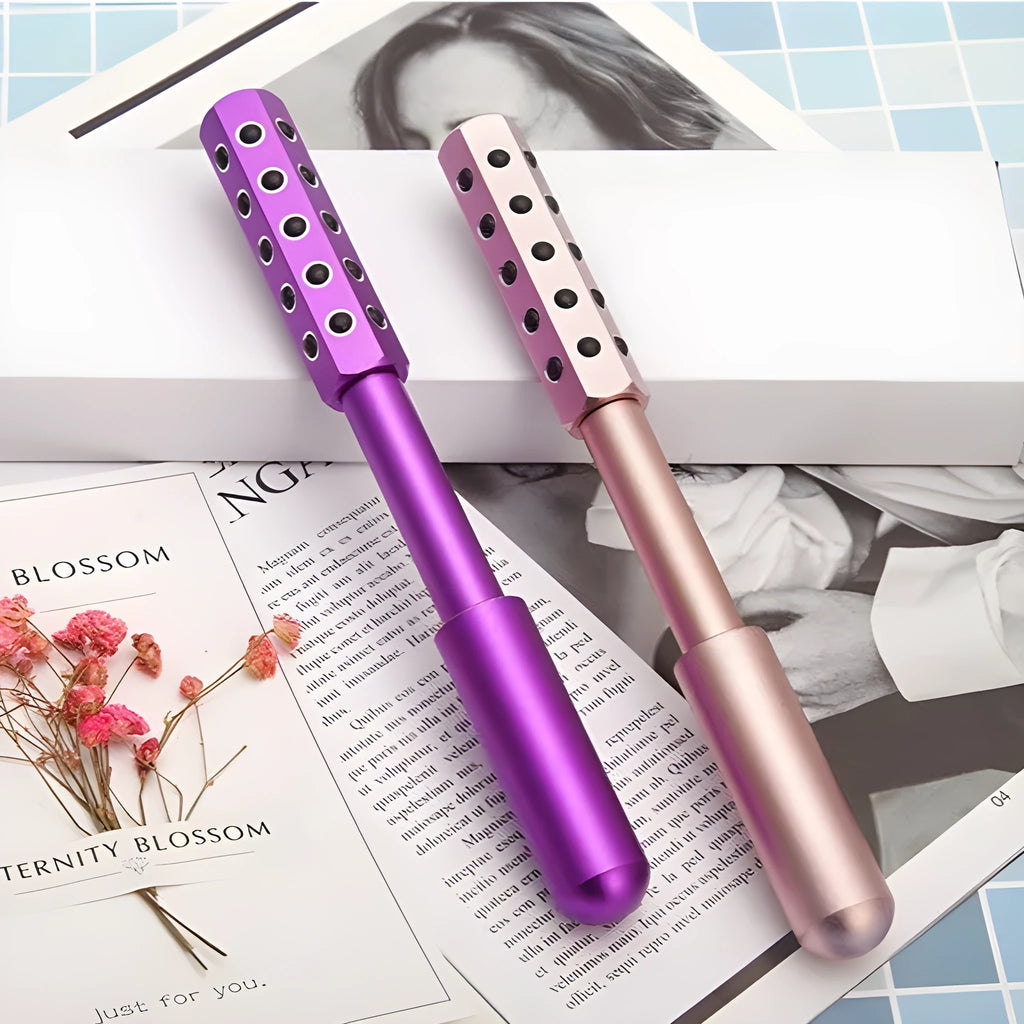 Purple handheld facial massage roller with textured surface on a white background.