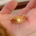 Open-mouth geometric women's ring with gold plating and pink crystal enamel detail on a white background.