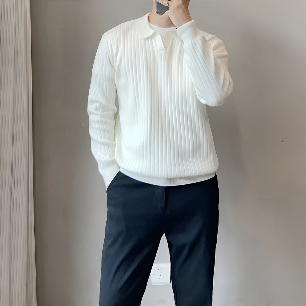 Man wearing a loose grey knitted pullover sweater with long sleeves, showing textured fabric detail.
