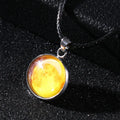 Close-up of a luminous alloy necklace with a blue organic glass constellation pendant on a model.