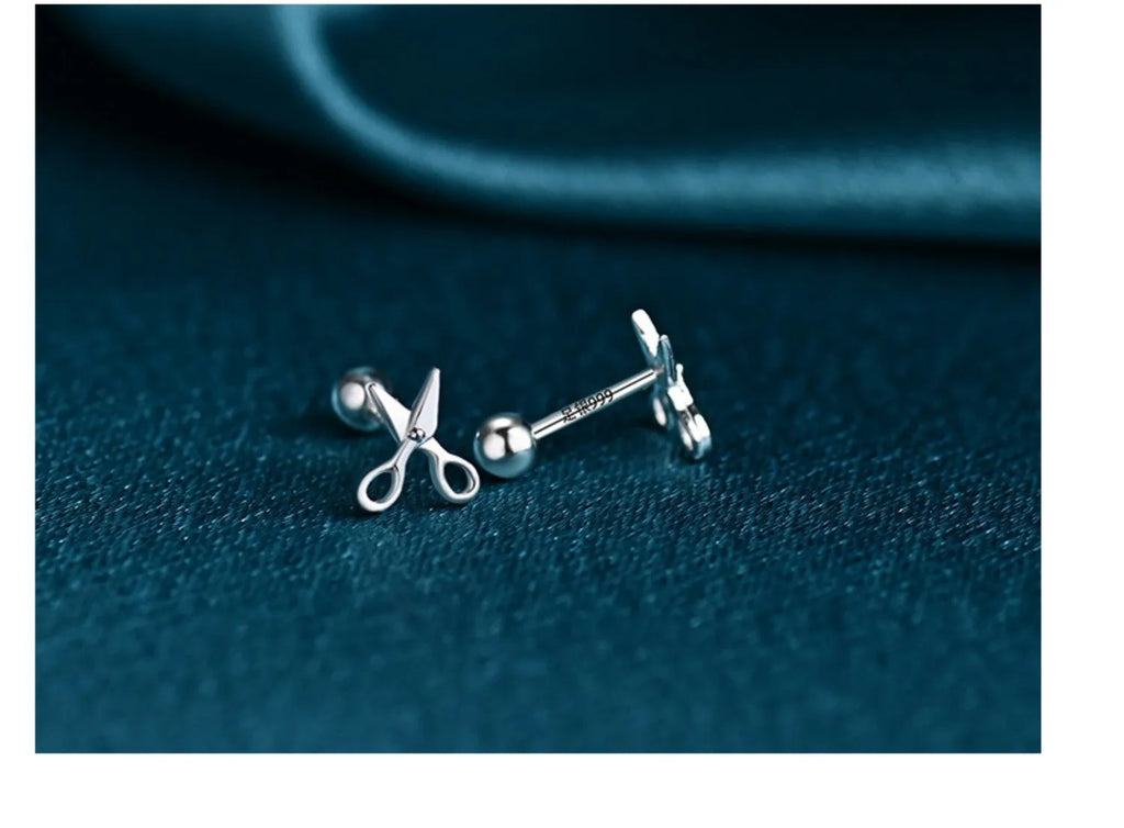 A pair of pure silver screw-back ear nails with a miniature scissors design.