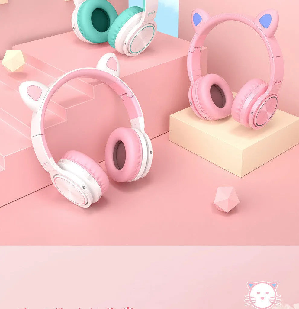 Pink and white wireless Bluetooth over-ear headset with a braided cable on a grey background.